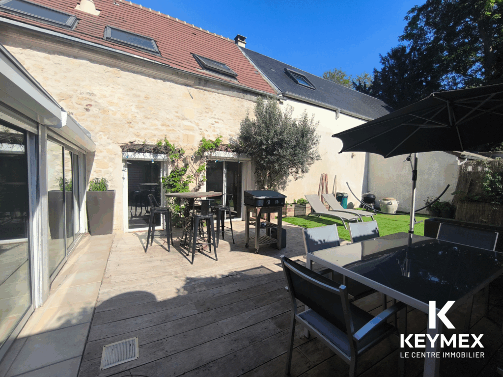 Terrasse ensoleillée avec mobilier de jardin et barbecue.