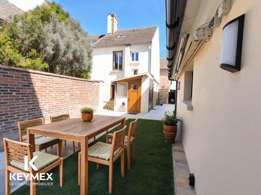 Jardin aménagé avec table et chaises en bois.